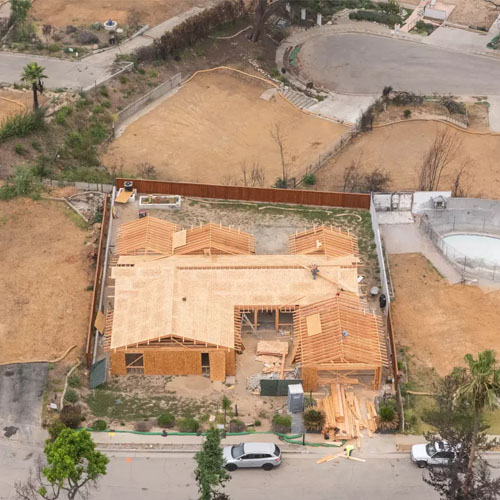 An aerial view of a home under construction on a leveled dirt property