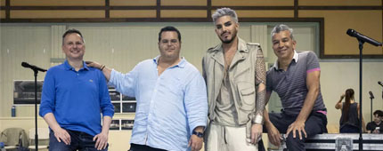 Brian Grohl, Josh Gad, Adam Lambert and Sergio Trujillo stand in a rehearsal room in front of black road boxes.