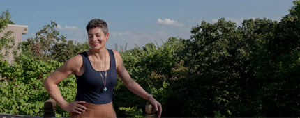 A woman in a tank top poses for a portrait on the back deck of her home. A woman in a tank top poses for a portrait on the back deck of her home.