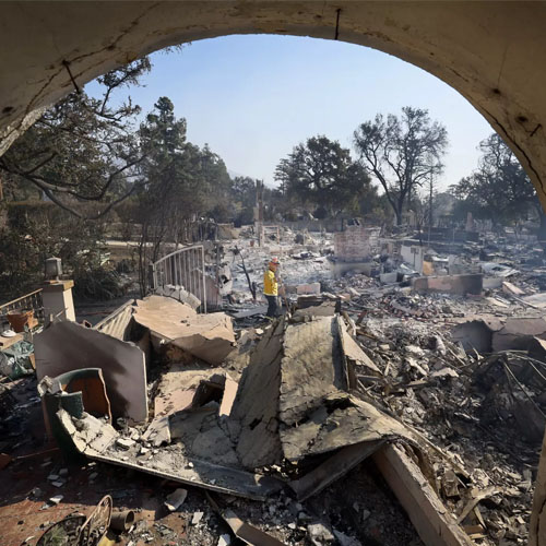 A firefighter stands among rubble.