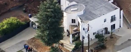 A large law enforcement operation is seen unfolding outside a home.