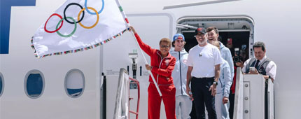 Mayor Karen Bass hoists the official Olympic flag near the hatch of an aircraft Mayor Karen Bass hoists the official Olympic flag near the hatch of an aircraft
