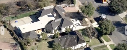 aerial photo of a large gray and white house with emergency vehicles parked outside
