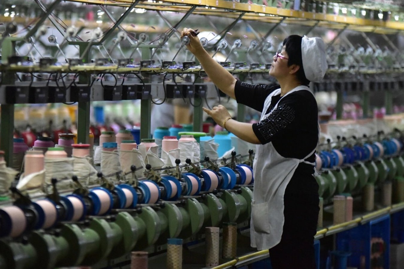 A worker checks a machine at a factory that produces silk cloth in Fuyang, China.