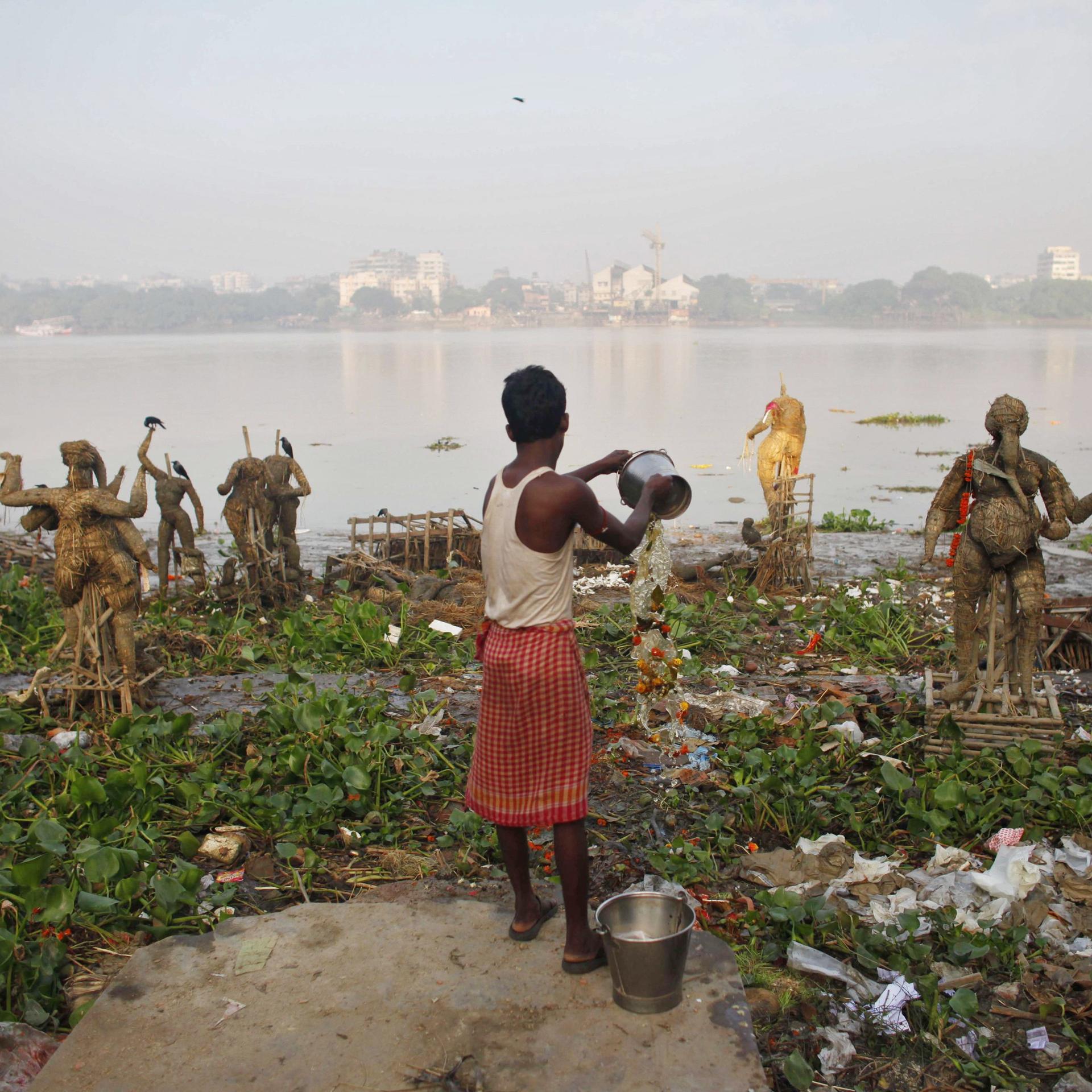 A man pours water on the polluted banks of the Ganges River, in Kolkata, India, on October 20, 2010.