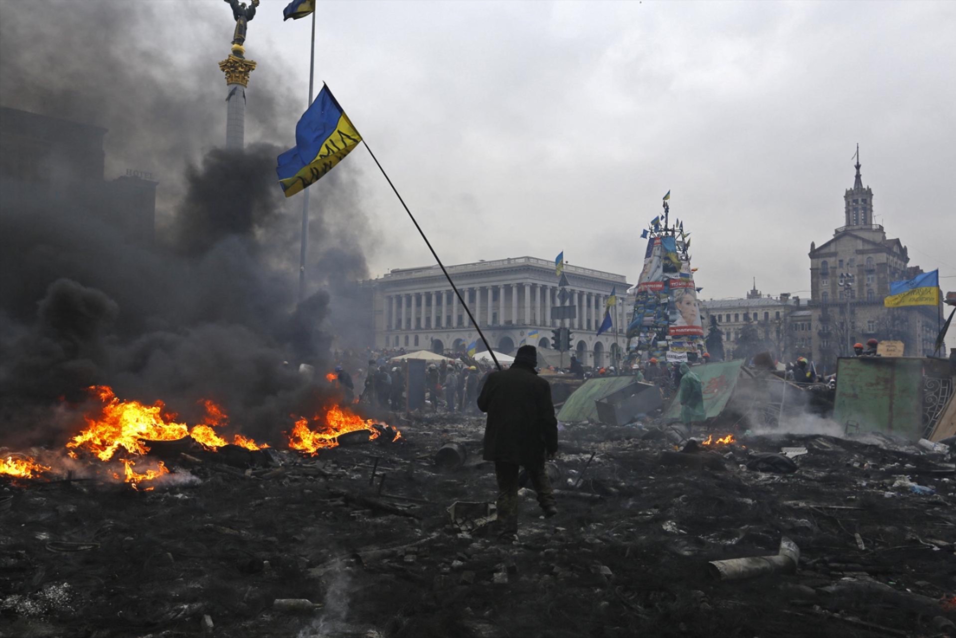 An anti-government protester carry the national flag as he walks trough the rubble after violence erupted in the Independence Square in Kiev February 20, 2014.