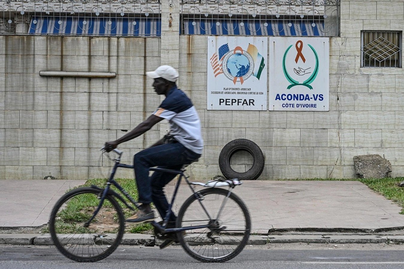       A man rides past a PEPFAR sign in the city of Abidjan, Ivory Coast, July 12, 2025. A man rides past a PEPFAR sign in the city of Abidjan, Ivory Coast, July 12, 2025.