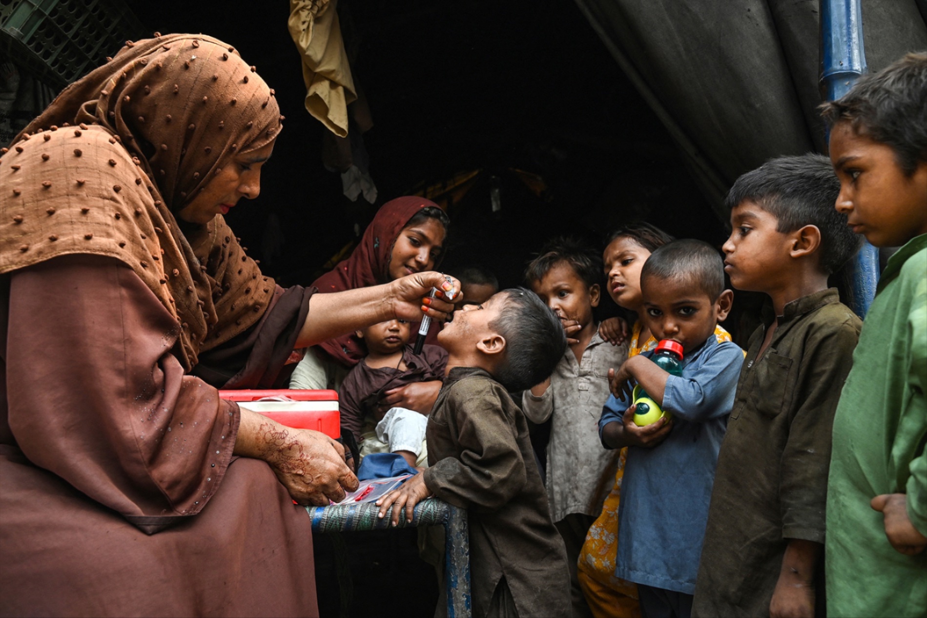 A woman administers drops of a polio vaccine into a young boy's mouth, as children stand by, waiting to be vaccinated themselves. Arif Ali/AFP/Getty Images