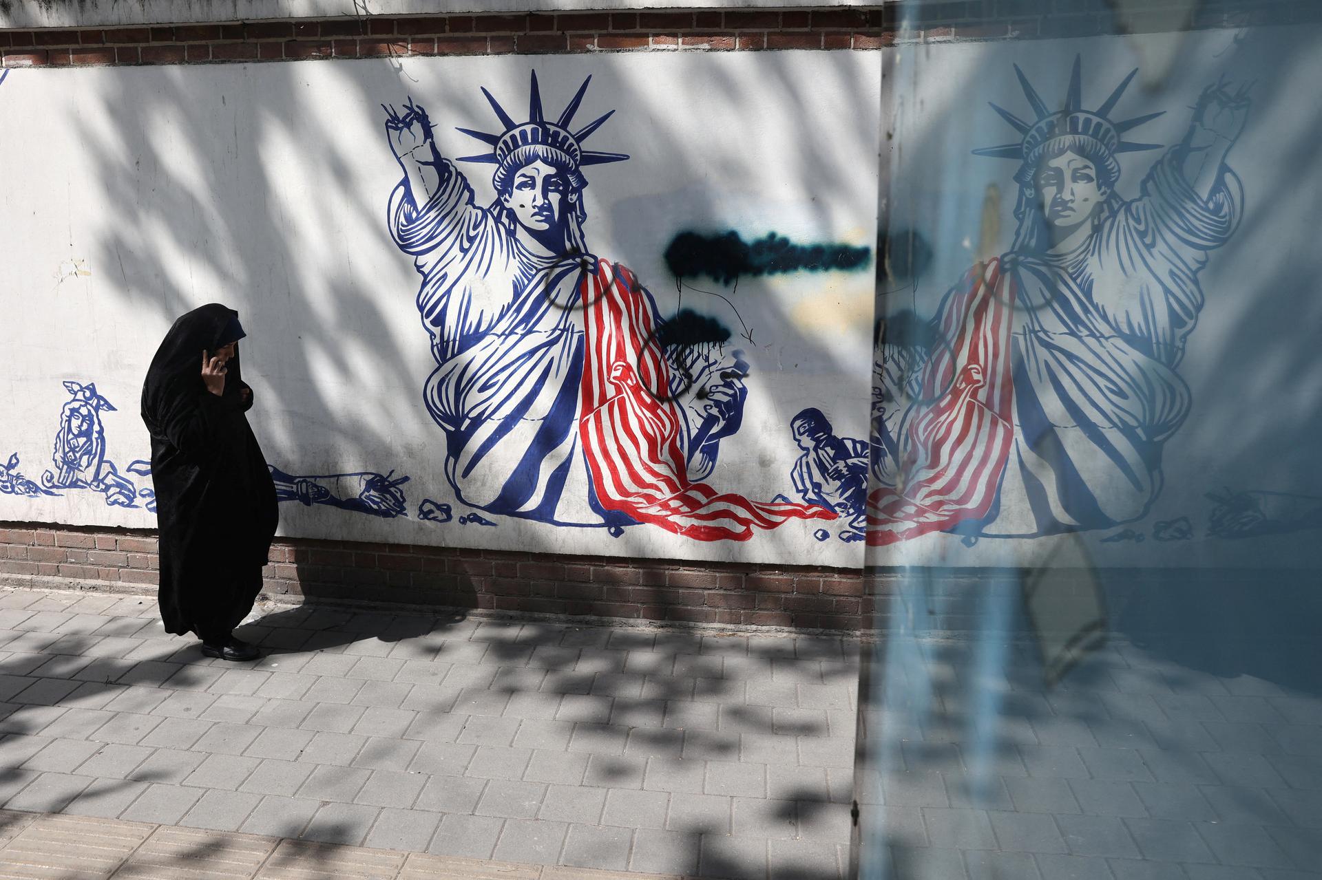 A woman walks next to an anti-U.S. mural on a street in Tehran, Iran, April 8, 2025.