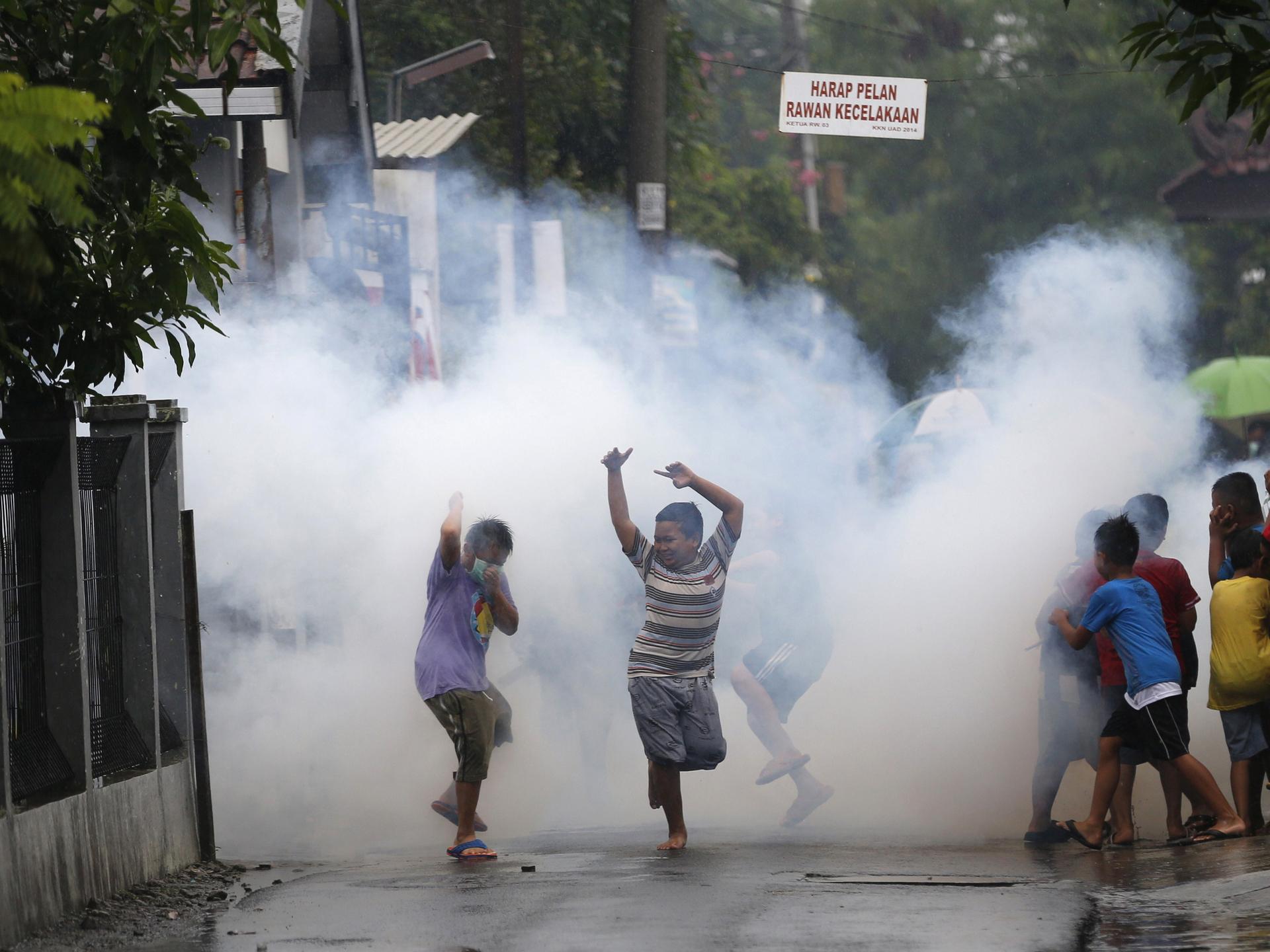 Children watch and play near a worker who is using the traditional method of chemical fogging to kill mosquitoes, in Yogyakarta, Indonesia, on February 5, 2016. 