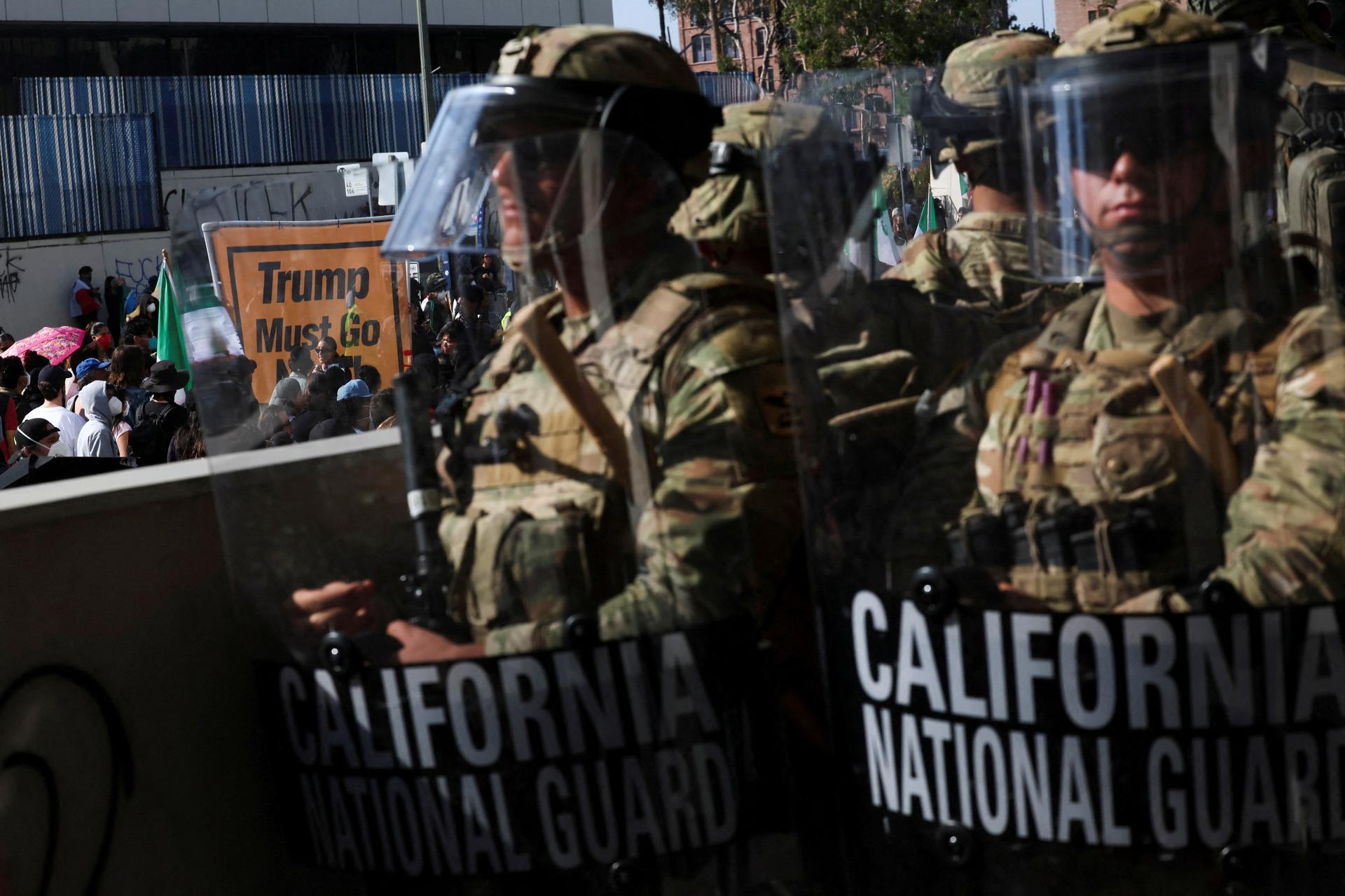 Members of the California National Guard stand in a line, blocking an entrance to the Federal Building, as demonstrators gather nearby, during protests against immigration sweeps, in Los Angeles, California, U.S. June 9, 2025. 