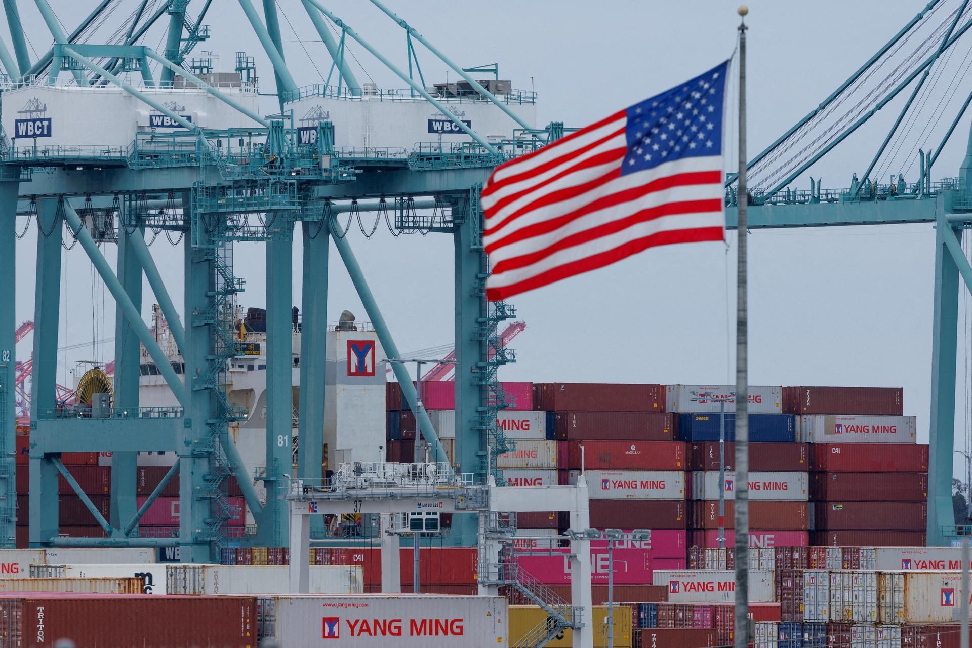 A U.S. flag flutters near shipping containers as a ship is unloaded at the Port of Los Angeles, in San Pedro, California, May 1, 2025.
