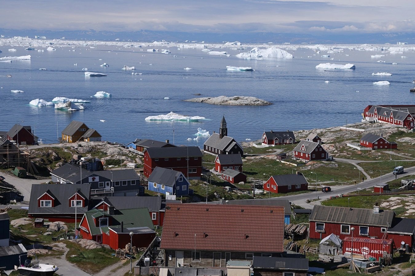 Houses stand as icebergs drift by in Disko Bay on July 15, 2024 in Ilulissat, Greenland. 