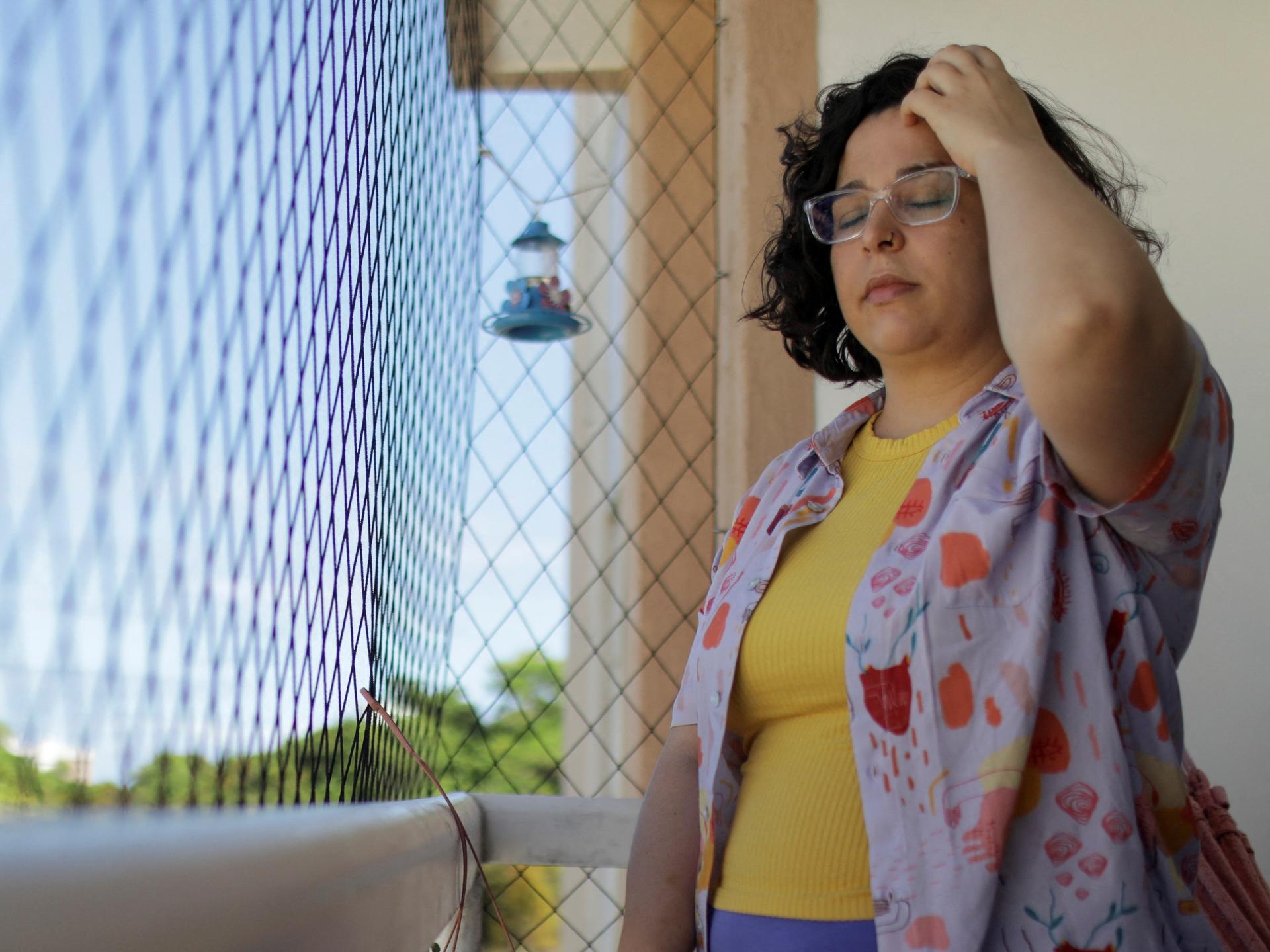 Leticia de Souza Soares, who suffers from pain and health problems caused by long COVID-19, stands on the balcony of her home, in Salvador, Brazil, on December 8, 2023. 