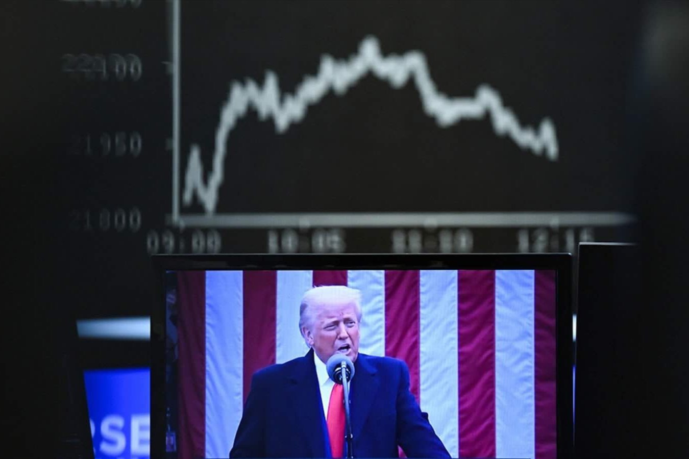 Behind a television monitor showing U.S. President Donald Trump, the display board with the Dax curve shows falling share prices on April 3, 2025 in Frankfurt, Germany. 