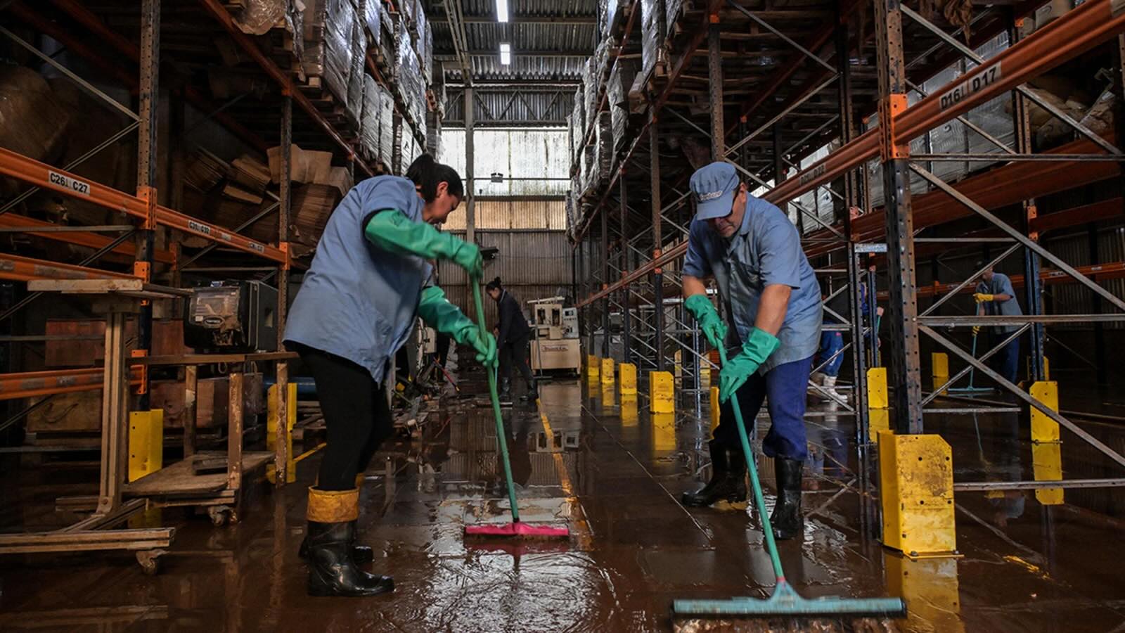 Workers remove mud accumulated by flooding at an industrial plant in Rio Grande do Sul, Brazil.
