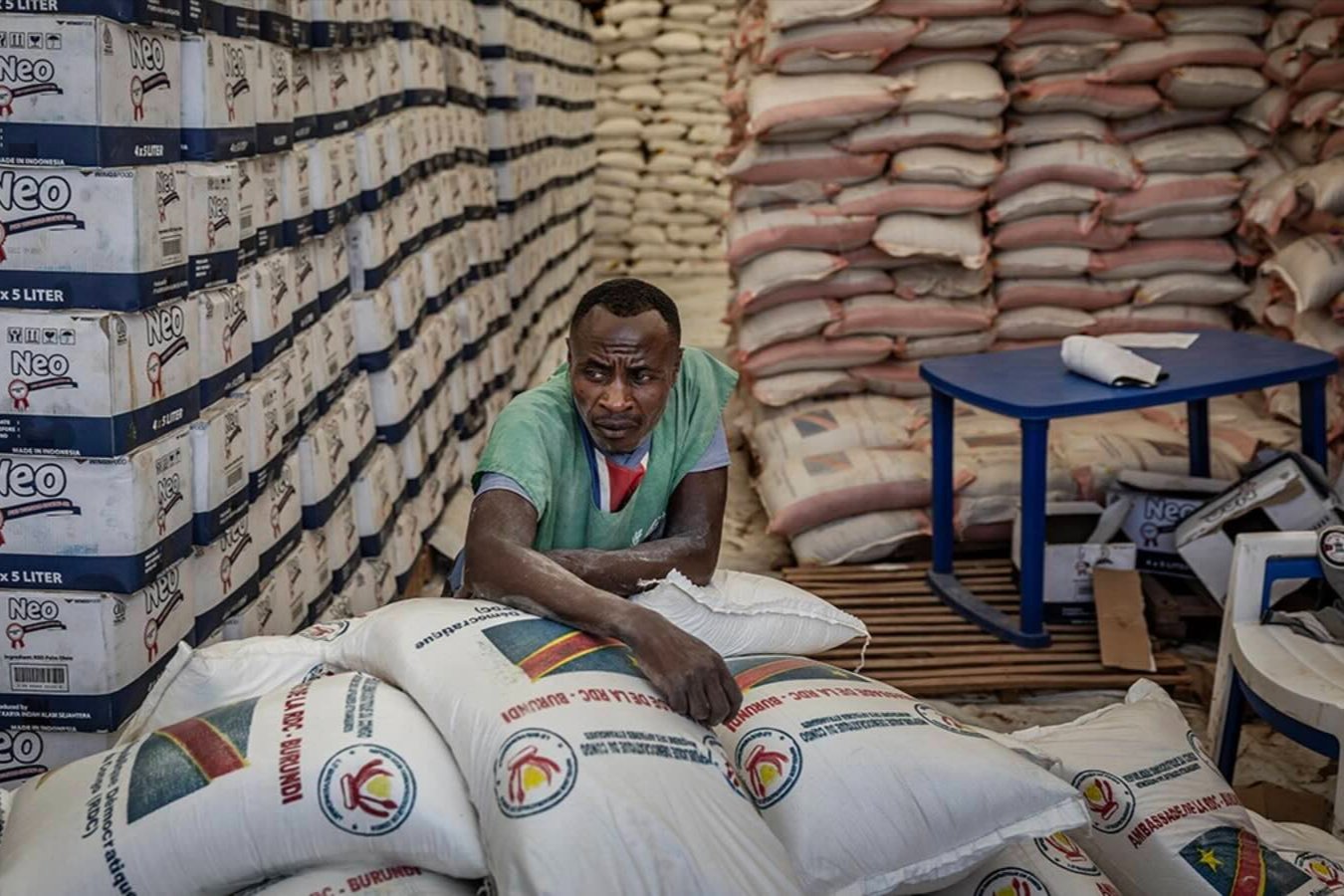 A worker rests on top of sacks of aid stacked in a storage tent as Congolese refugees gather waiting for a chance to receive food assistance in Giharo, Democratic Republic of Congo.