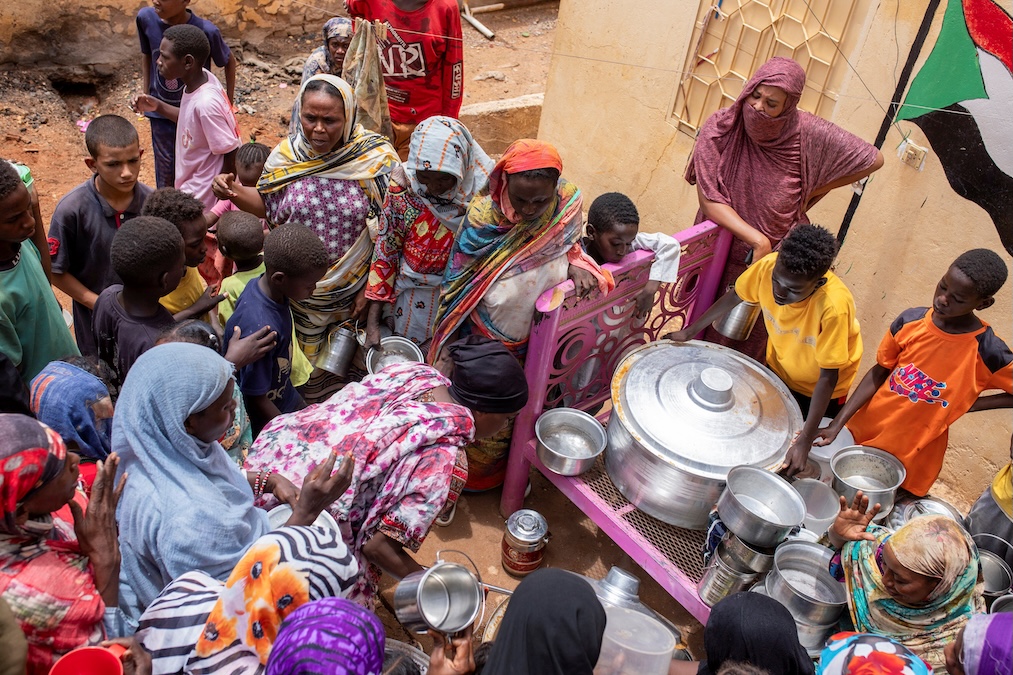 Women from community kitchens distribute meals to those who are affected by conflict and extreme hunger and out of reach of international aid efforts, in Omdurman, Sudan, on July 27, 2024. (Mazin Alrasheed/Reuters)