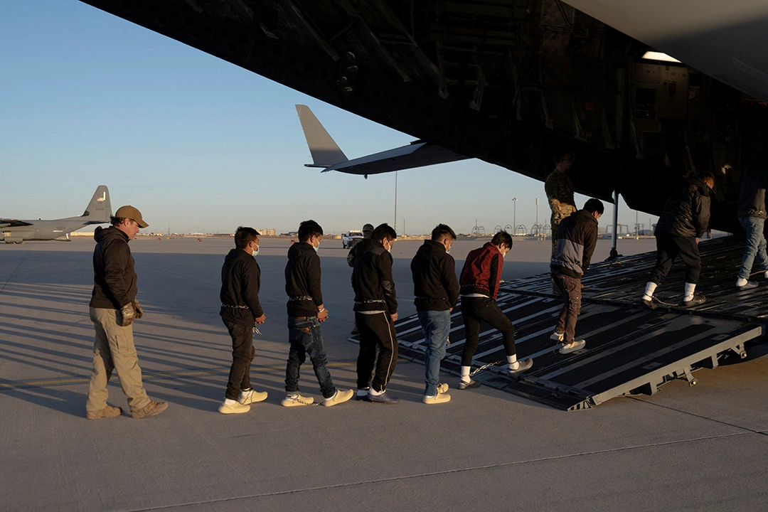 Customs and Border Protection agents guide detained migrants aboard a U.S. aircraft at Fort Bliss, Texas.