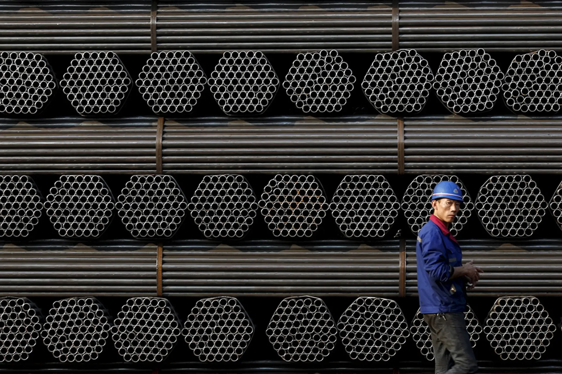 A worker stands in front of steel piping at a plant in China's Hebei Province