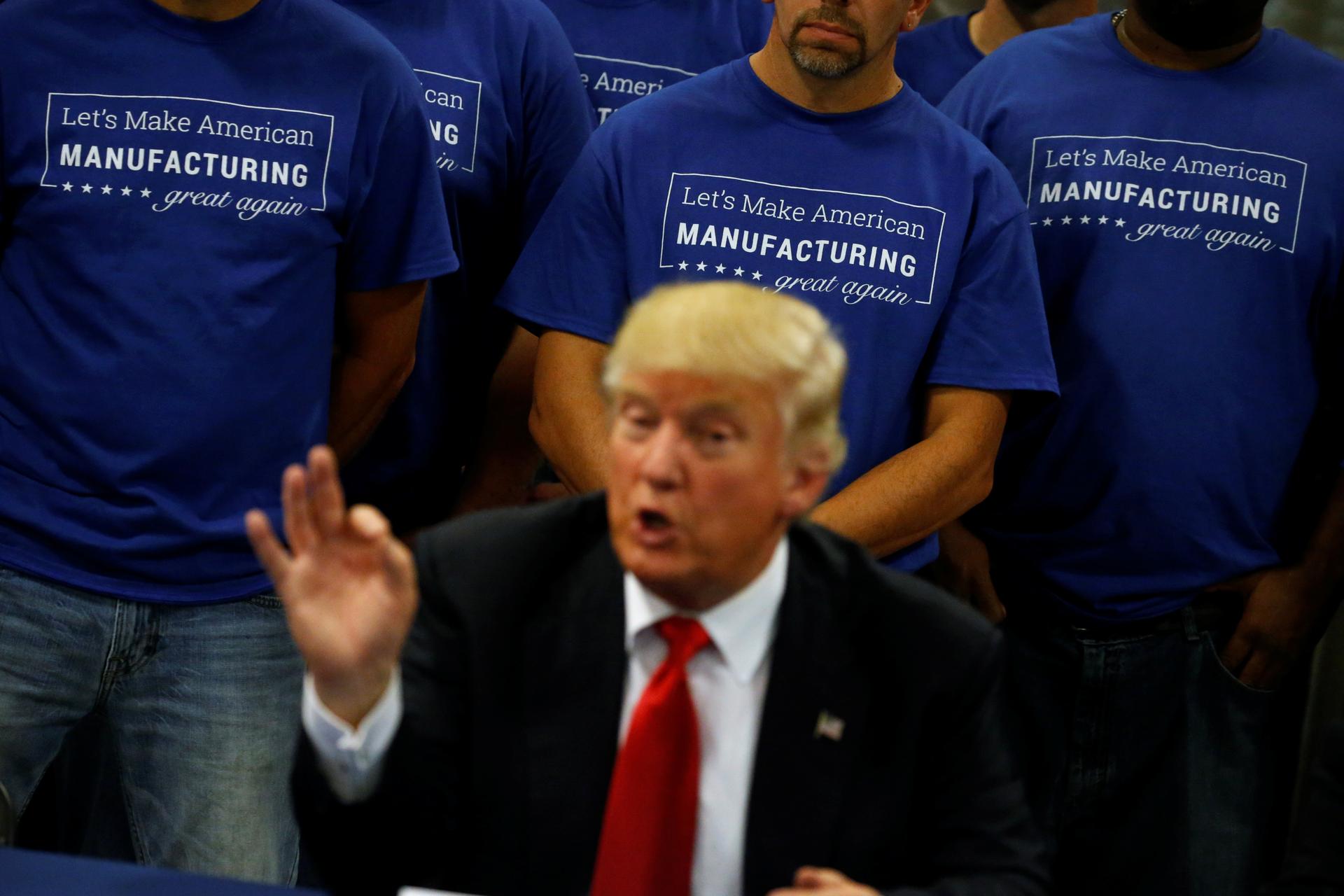 Workers stand behind Trump during a business roundtable at the Staub Manufacturing plant in Dayton, Ohio, U.S.
