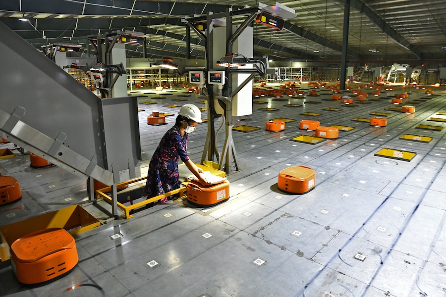 A worker uses AGV's (Automated Guided Vehicles) at Flipkart, a leading e-commerce firm in India, to sort items inside its fulfilment centre on the outskirts of Bengaluru, India, September 23, 2021. (Samuel Rajkumar/Reuters)