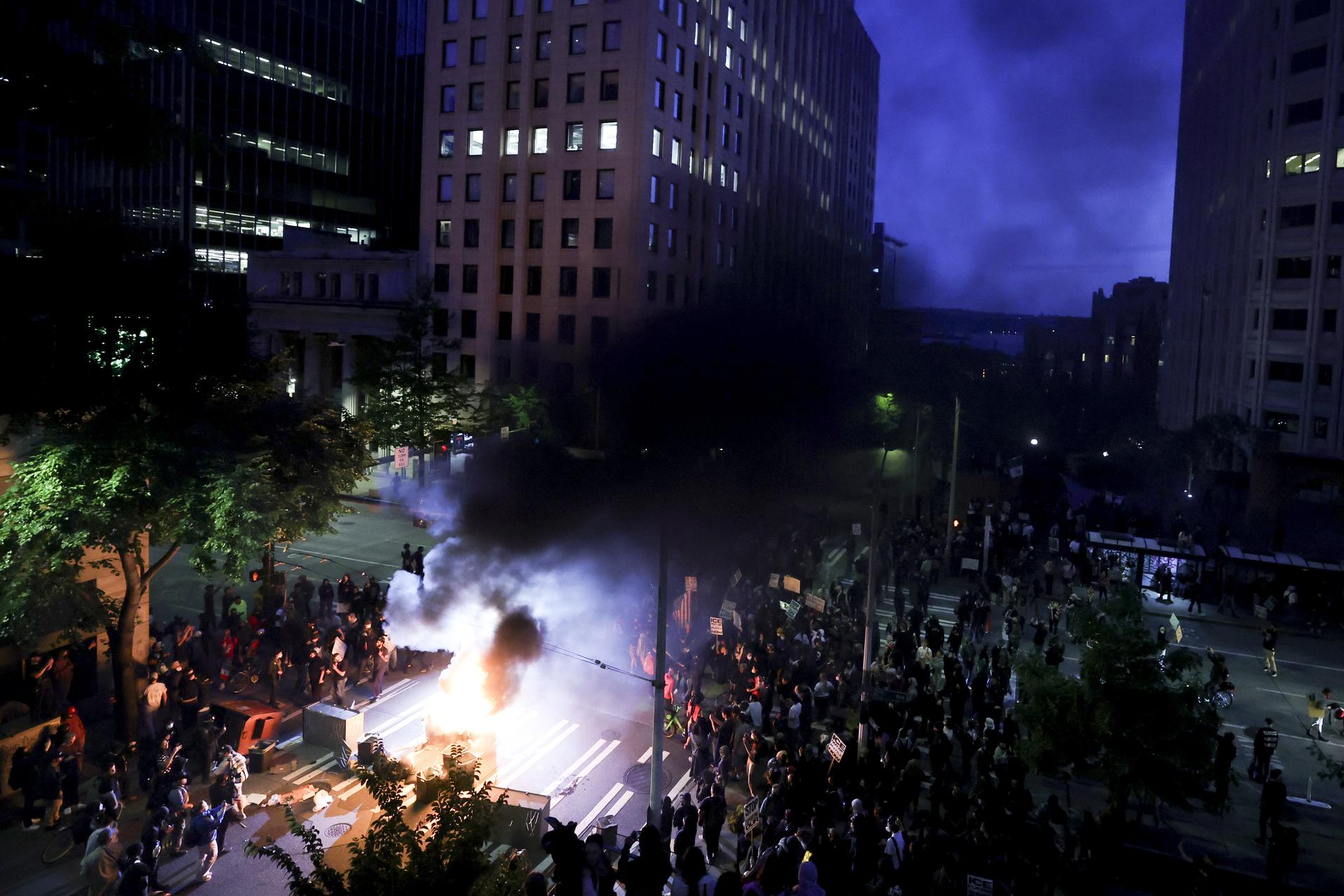 Protestors surround a dumpster that was set on fire in front of the Henry M. Jackson Federal Building during a protest against federal immigration arrests Wednesday in Seattle.