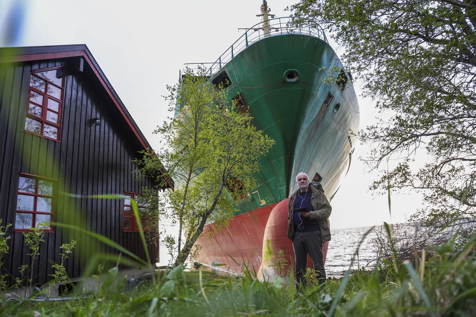 Johan Helberg stands next to his house, with the container ship NCL Salten in the background, in Trondheim, Norway.