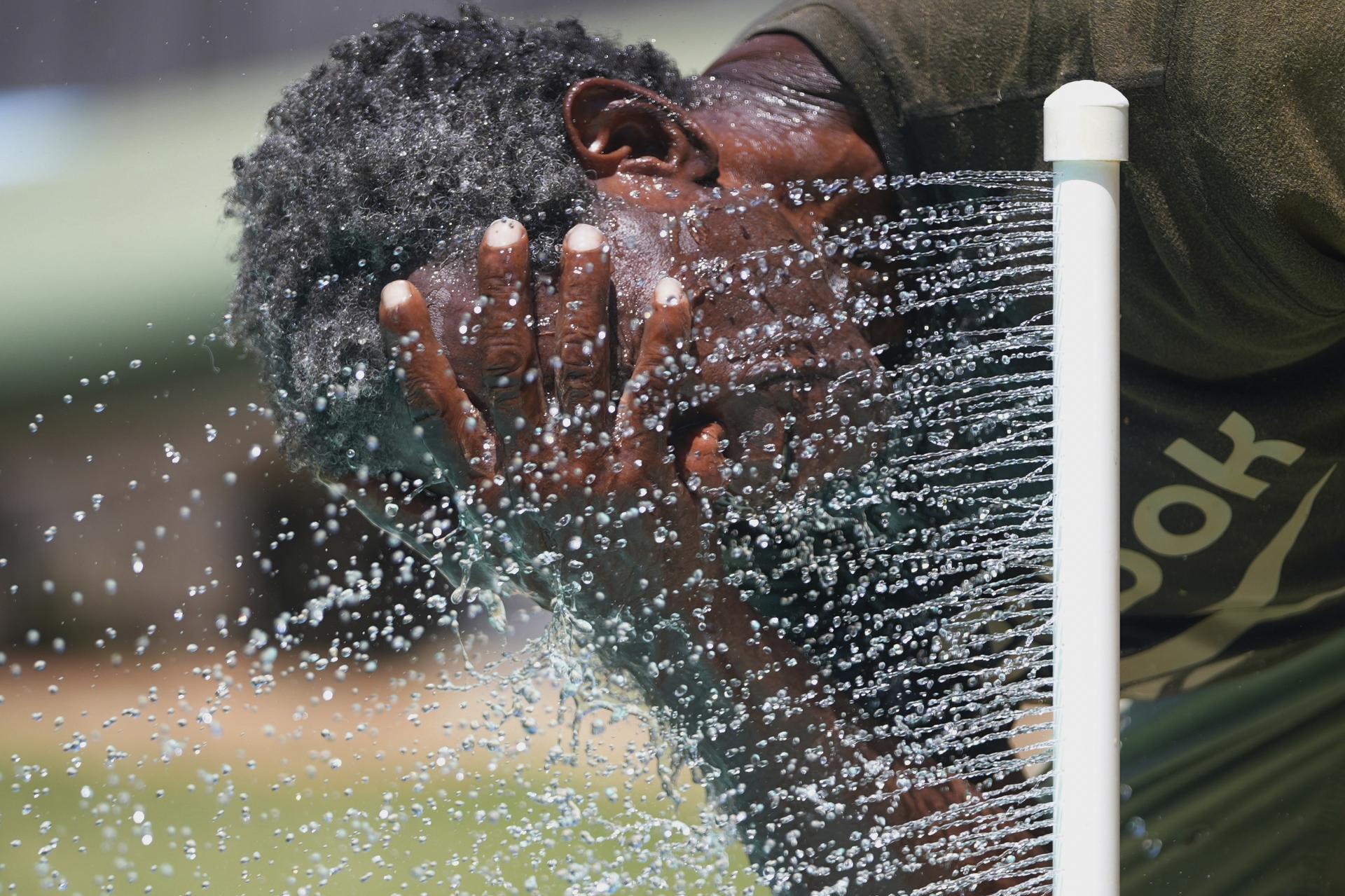 Paul Williams cools off in water while taking a break from yard work in Richardson, Texas, July 31, 2025. (AP Photo/LM Otero)