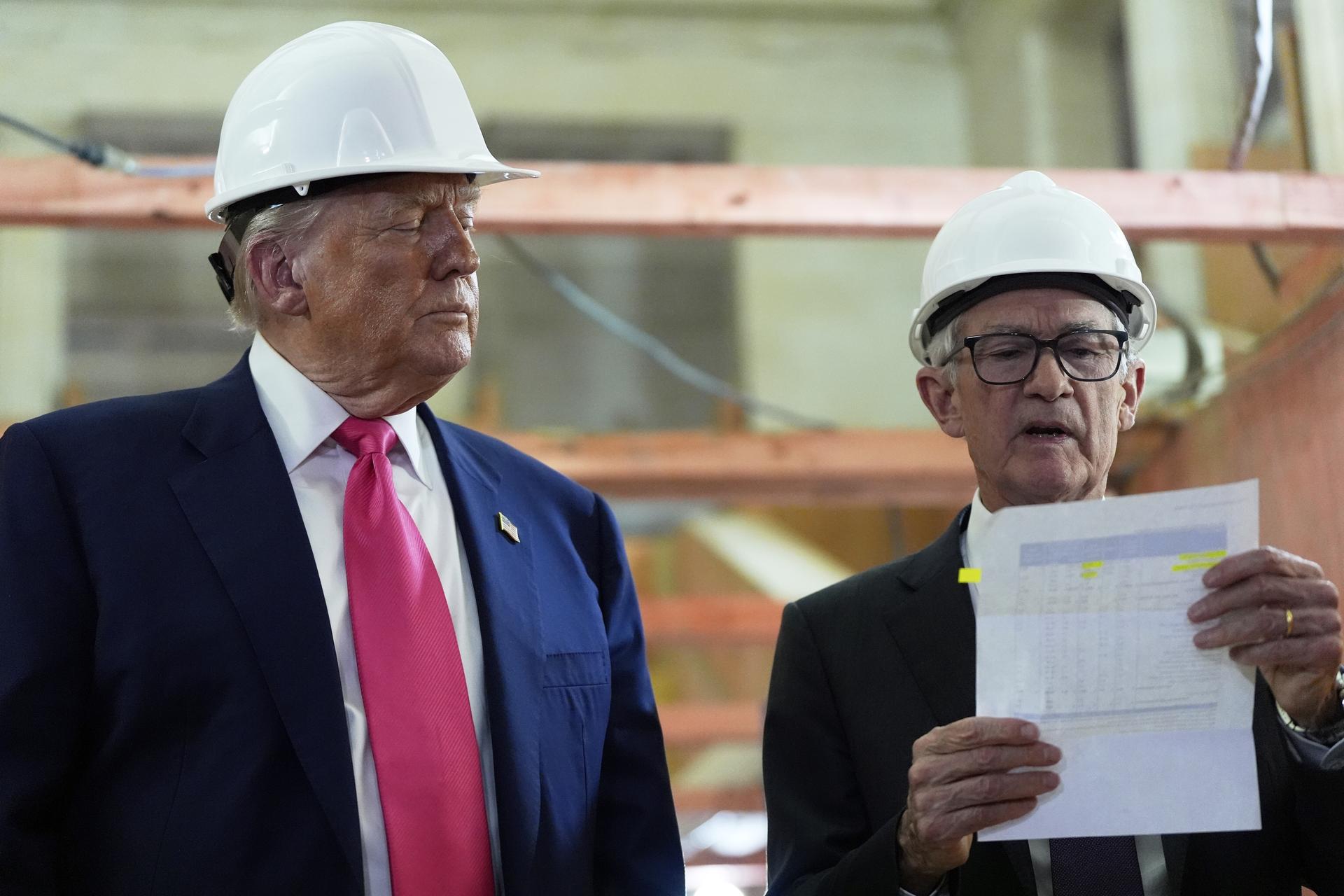 Federal Reserve Chairman Jerome Powell reviews a document of cost figures as President Donald Trump watches during a visit to the Federal Reserve on Thursday in Washington. 