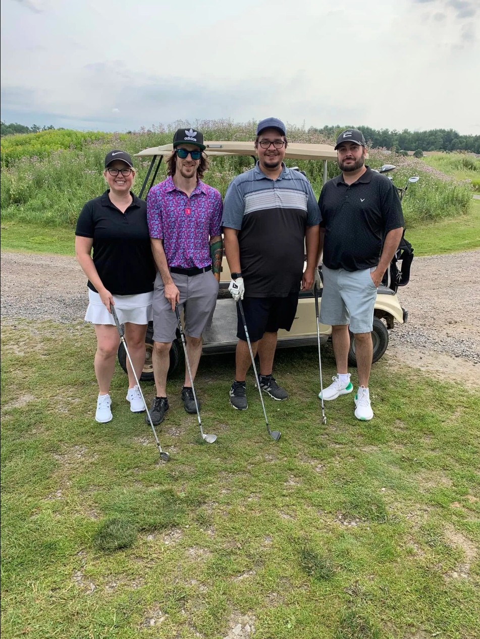 Three golf players in front of a cart.
