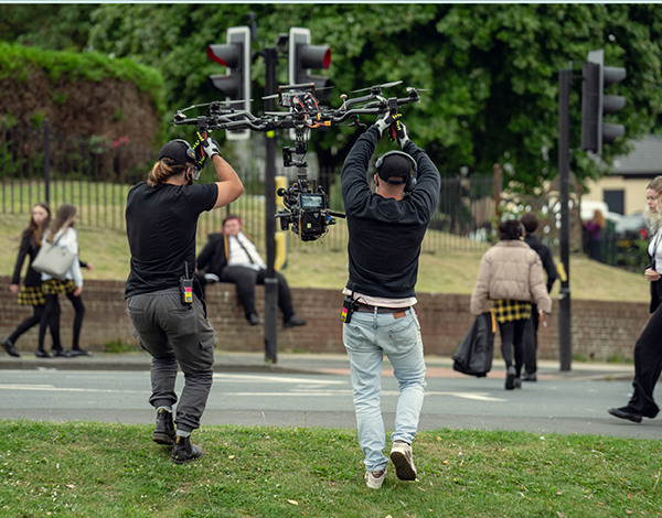A film crew working outside near a school.