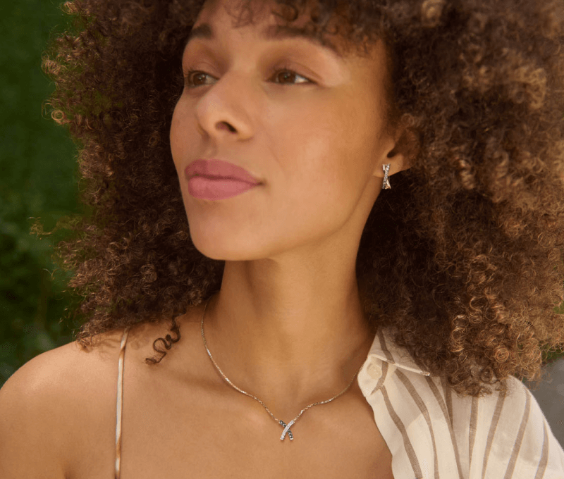 A woman showcases a delicate necklace and earrings