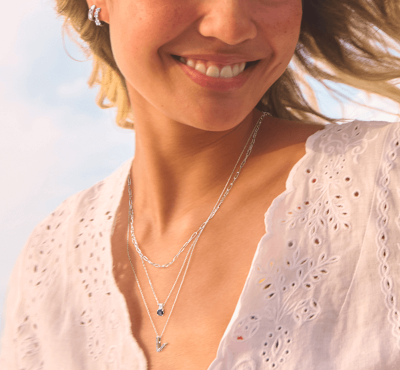 A woman smiles showcases stunning necklaces, and earrings