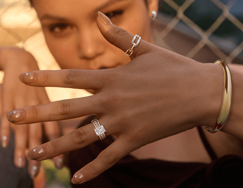 A woman holds a hand up to the camera to showcase beautiful rings and a bracelet