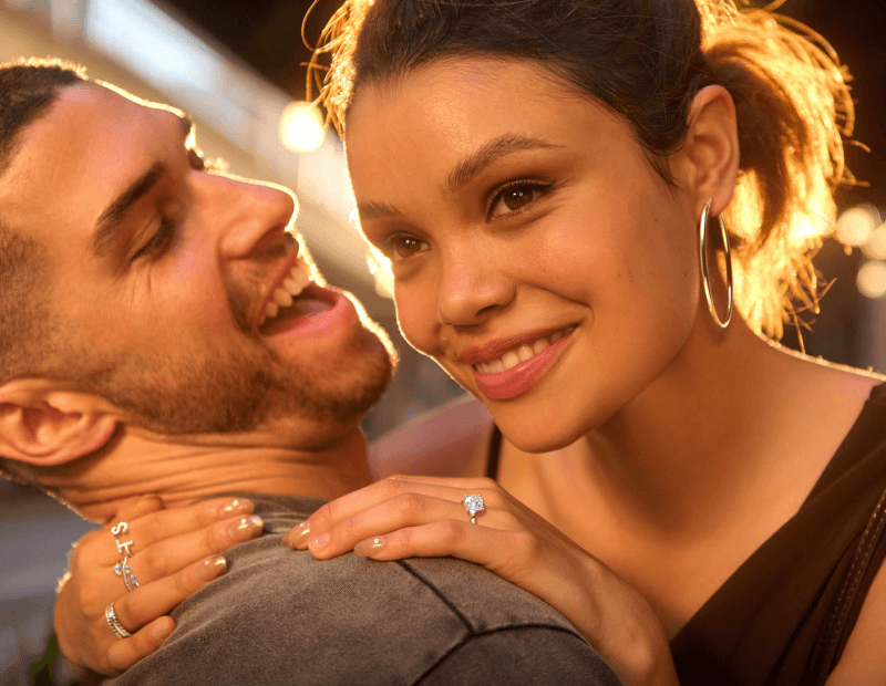 A couple embrace and we see stunning rings on the woman's hand