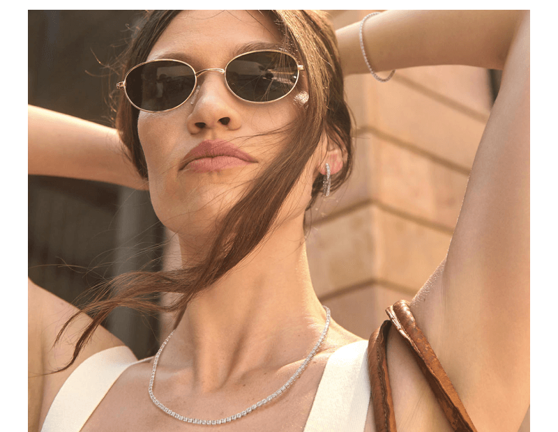 A woman holds her hair up to reveal a stunning tennis necklace