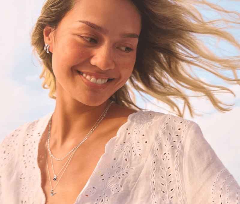 A woman wearing stunning necklaces and earrings gazes downwards