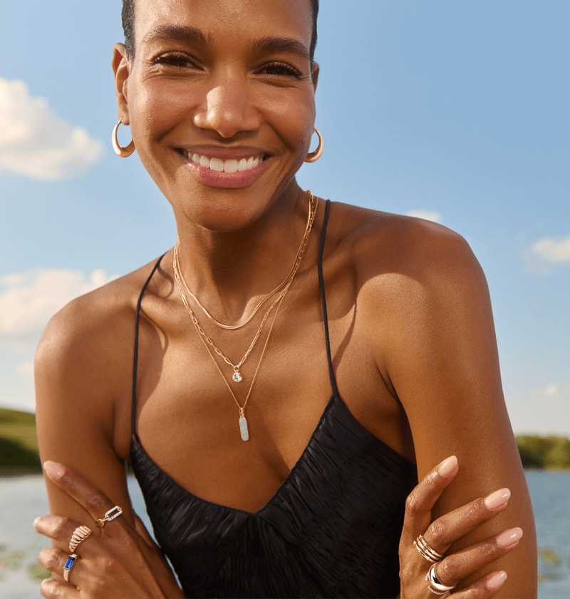 A woman smiles and crosses her arms to reveal stunning rings, necklaces and earrings