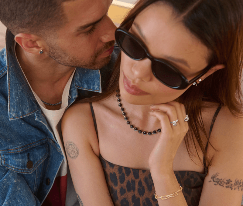 A man and a woman lean into each other, showcasing stunning jewelry