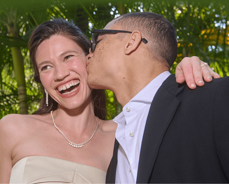 A man kisses a woman wearing stunning jewelry on the cheek