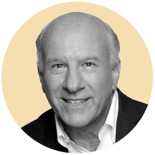 A headshot of Adi Ignatius in front of a gold background.