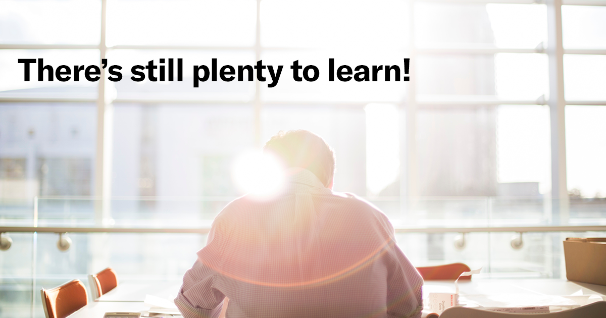 A person sitting at a desk in front of a large window and the text overlay, “There’s still plenty to learn!”