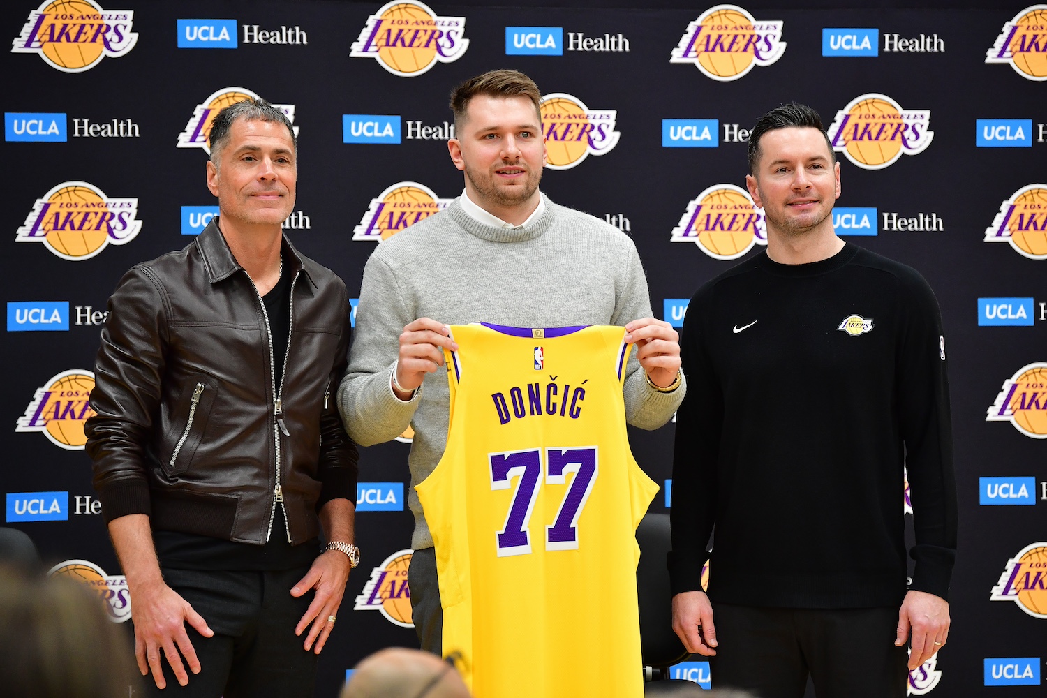 Luka Doncic holding up a Lakers jersey and standing beside his new head coach JJ Redick.