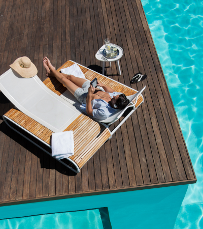 man lounging next to a pool, reading on his phone