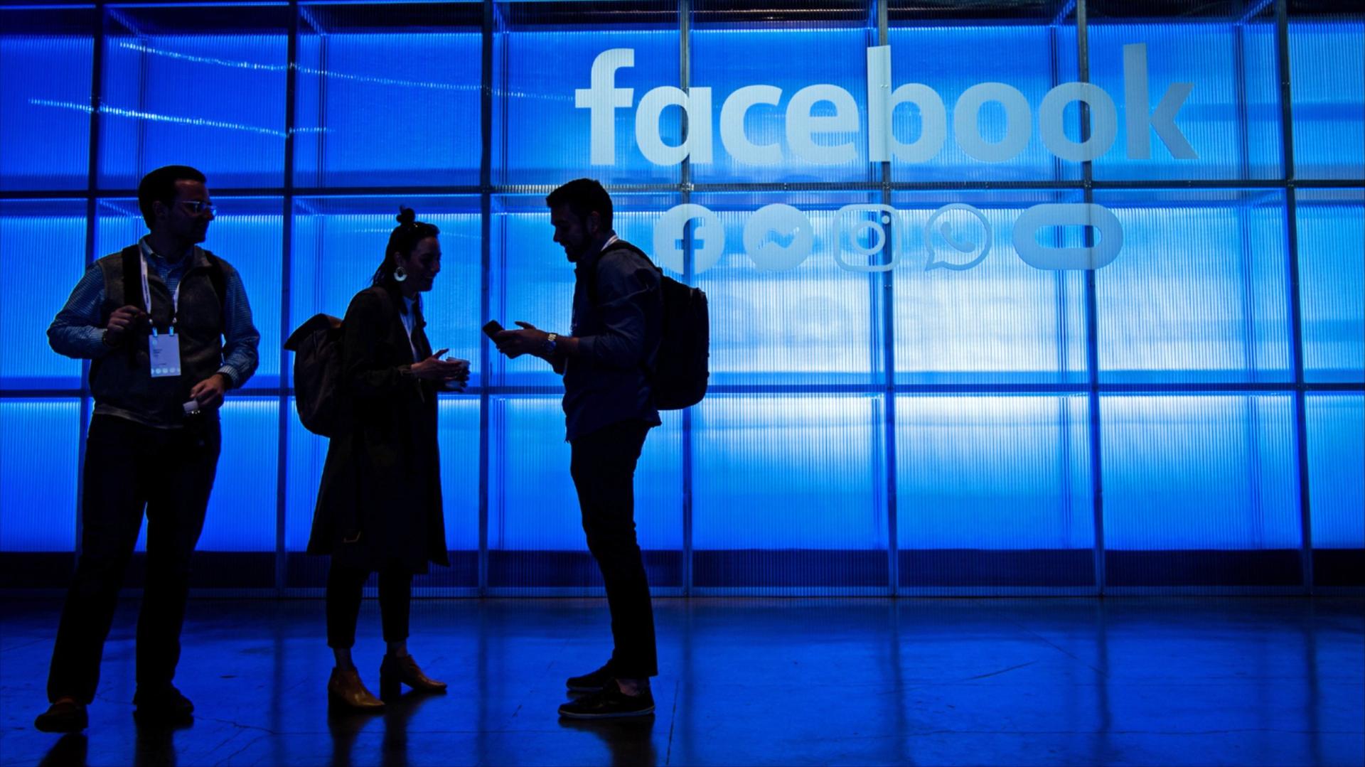 A photo of people standing in front of a Facebook sign