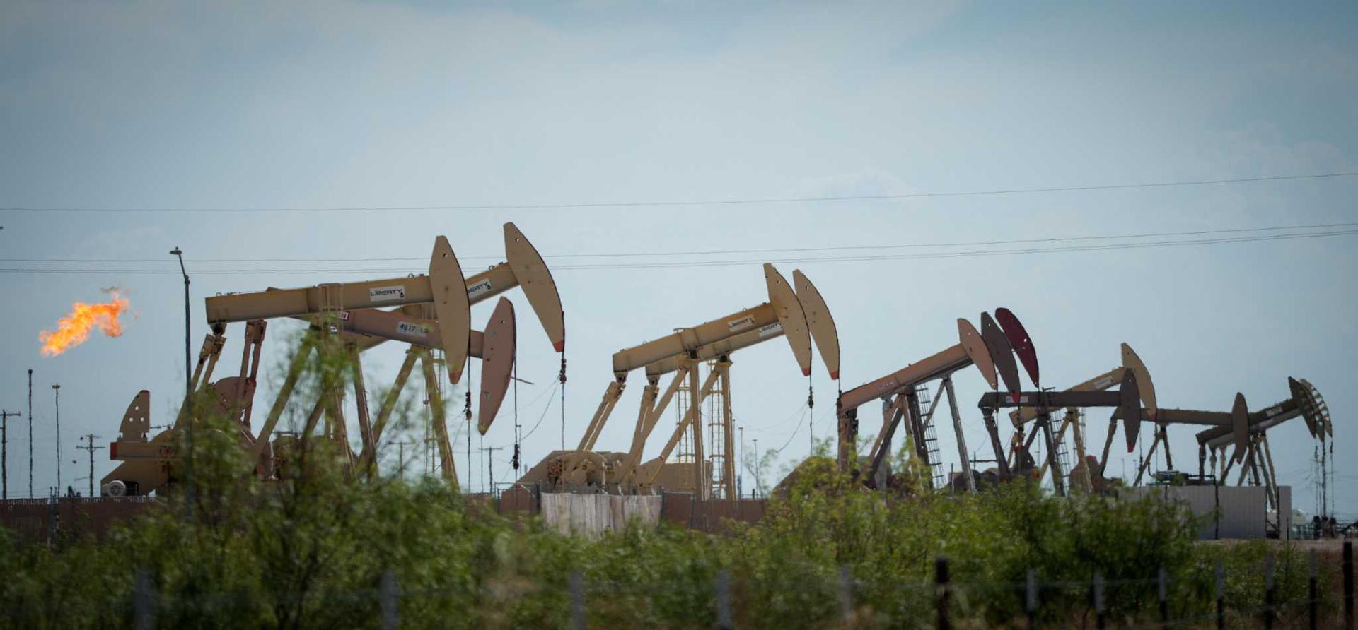 A flare burns near a row of pumpjacks in Midland, TX.
