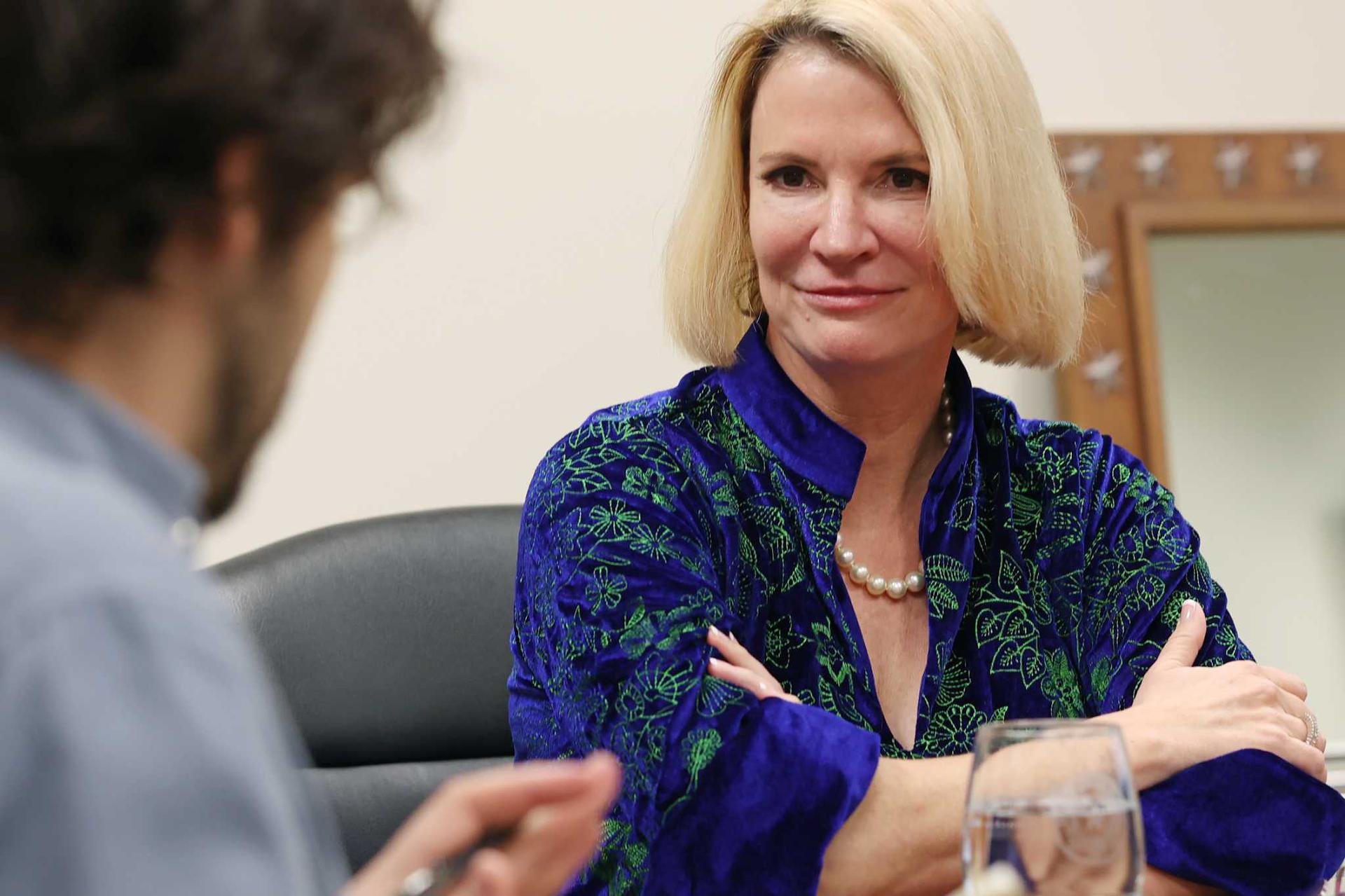 Dawn Buckingham in a blue top sits at a desk. 