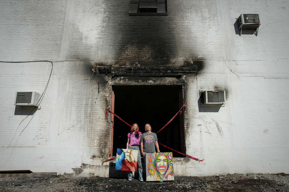 Artists Rebekah Molander, left, and Toria Hill, pose for a portrait in front of the smoke stained building that housed their studios.