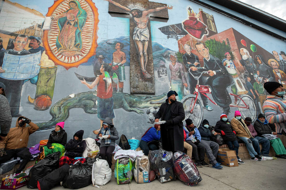 Migrants eat and wait for help while camping on a street in downtown El Paso, Texas.